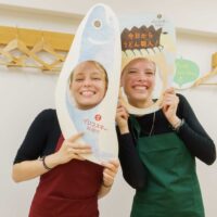 女性2人がイリコスキー製麺所の顔はめパネルを持って笑顔で記念撮影している 手打ちうどん作り体験教室 2025年12月 A6407349-1-scaled.jpg – イリコスキー製麺所