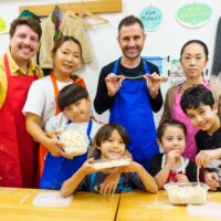 参加者が切った麺を手に、教室内で記念撮影している様子 手打ちうどん作り体験教室 2025年12月 A6407386-1-scaled.jpg – イリコスキー製麺所