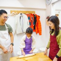 子どもが麺棒で生地をのばし、両親が近くで見守っている様子 手打ちうどん作り体験教室 2025年12月 A6407443-1-scaled.jpg – イリコスキー製麺所