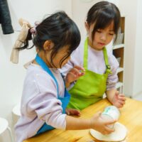 姉妹が打ち粉用の缶を傾けて、生地に粉をふりかけるうどん作り体験 手打ちうどん作り体験教室 2025年12月 A6407540-1-scaled.jpg – イリコスキー製麺所