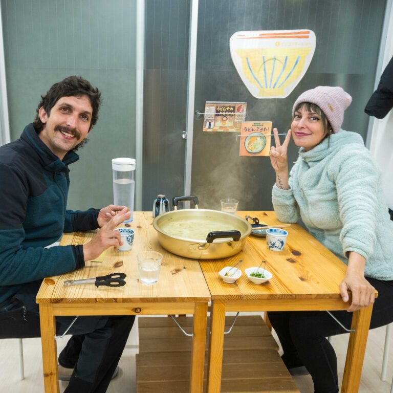 自分で作った釜揚げうどんを前にピースサインをするイタリア人のカップル (Italian couple making peace signs in front of their handmade Kama-age Udon) 手打ちうどん作り体験教室 2025年12月 1-1.jpg – イリコスキー製麺所
