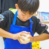 真剣な表情でうどんの生地を丸めるお兄ちゃん。 Big brother making a dough ball with a serious expression. 手打ちうどん作り体験教室 2026年1月 4.jpg – イリコスキー製麺所