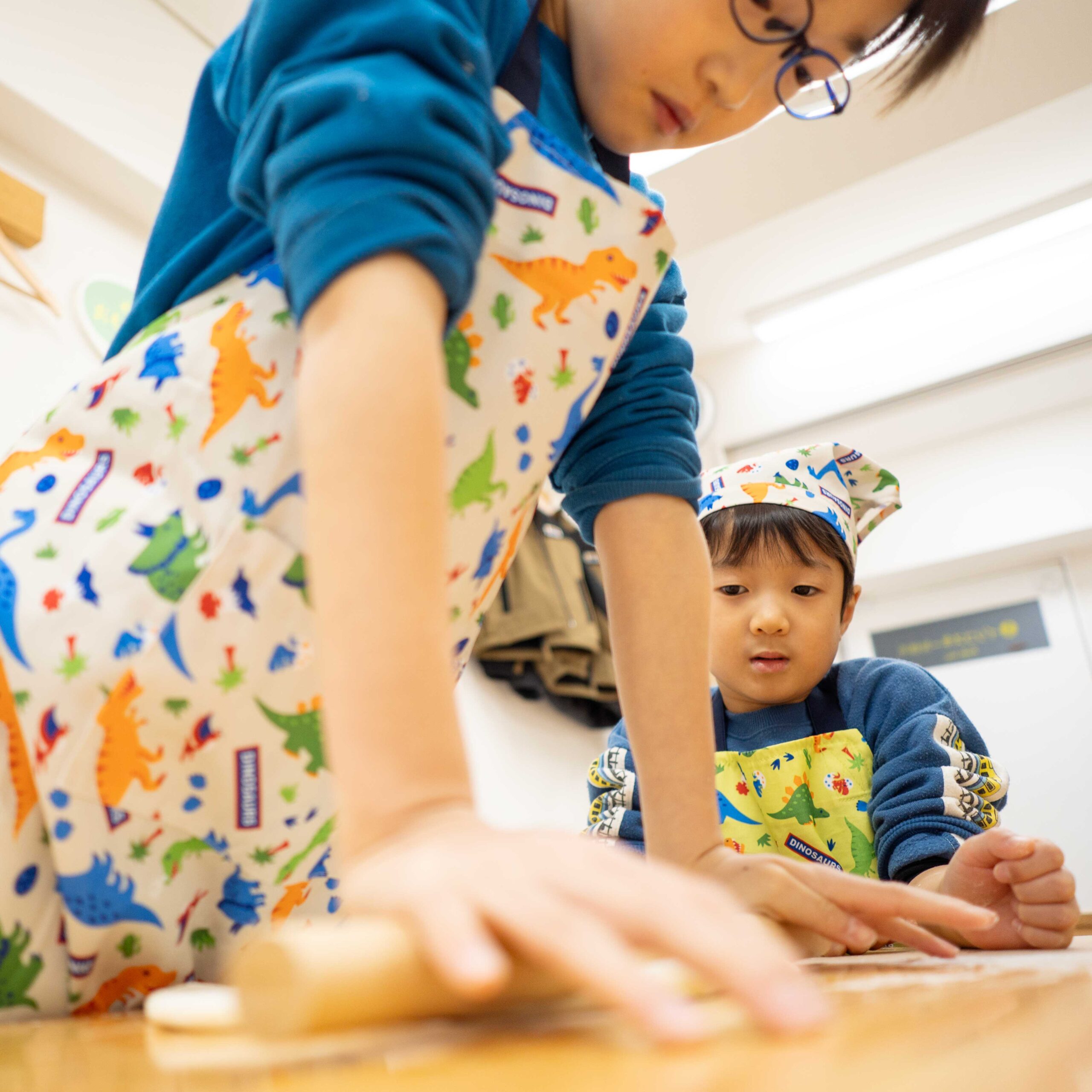 真剣な表情で麺棒を使って生地を伸ばす男の子。 Boy looking focused while rolling out the dough with a rolling pin. 手打ちうどん作り体験教室 2026年1月 A6408443-1-scaled.jpg – イリコスキー製麺所