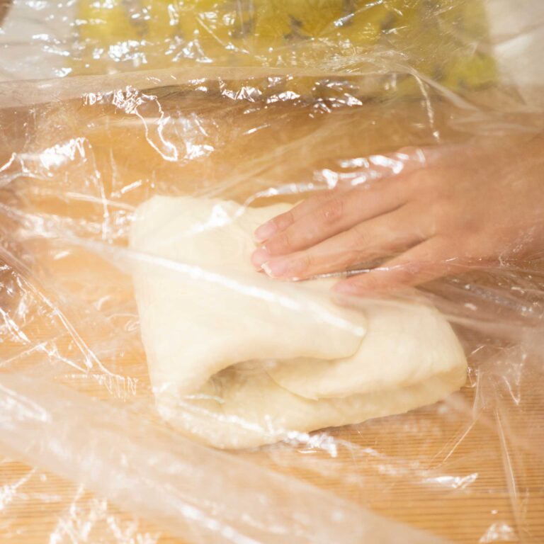 3回目の1年生、ひとりで完走！ 手打ちうどん作り体験教室 2026年1月 shaping-udon-dough-through-plastic-wrap.jpg – イリコスキー製麺所