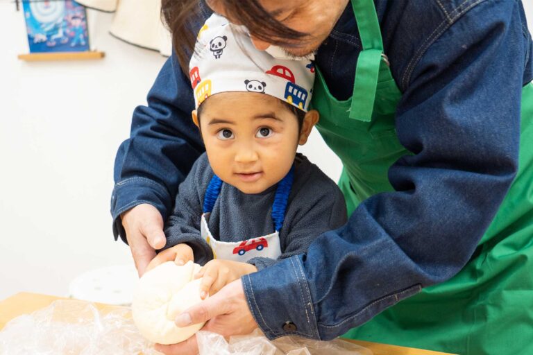 父に手を添えてもらいながら生地を丸める男の子。大きな目でカメラを見つめている。 手打ちうどん作り体験教室 2026年1月 udon-class-boy-shaping-dough-2.jpg – イリコスキー製麺所