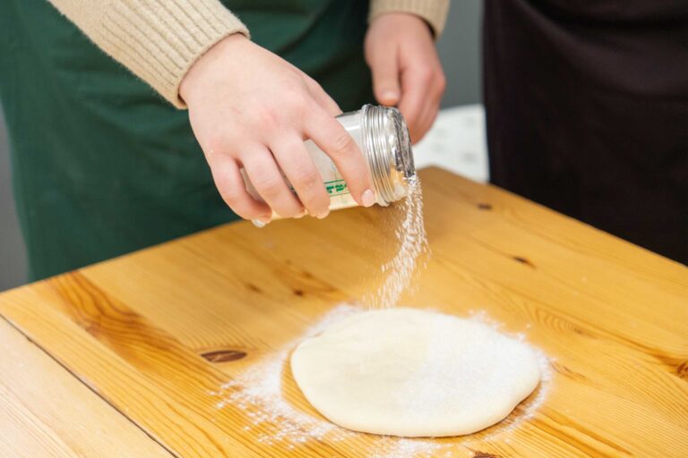 うどん体験教室で作業台の生地に打ち粉をふりかける手元 手打ちうどん作り体験教室 2026年1月 udon-class-dusting-flour.jpg – イリコスキー製麺所