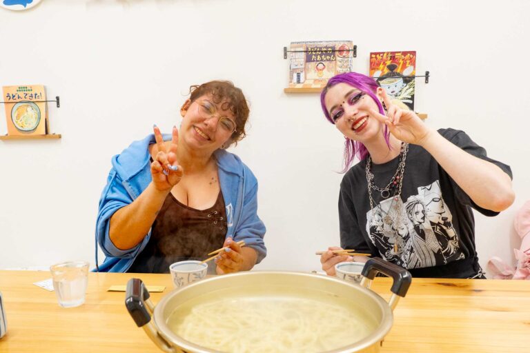 スイスからいらっしゃった女性2人が、できあがったうどんの大鍋の前でピースサインをして笑顔を見せている。 手打ちうどん作り体験教室 2026年2月 udon-class-peace-sign-finished-udon-pot.jpg – イリコスキー製麺所