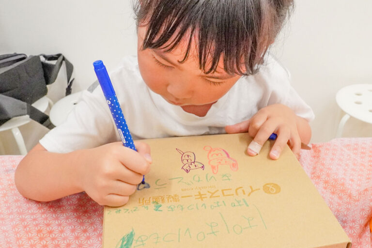 自分で打ったうどんを入れるギフトボックスに、女の子がカラーペンでメッセージやイラストを描いている。父の日のプレゼントづくり。 手打ちうどん作り体験教室 2026年3月 udon-class-girl-writing-fathers-day-gift-box.jpg – イリコスキー製麺所