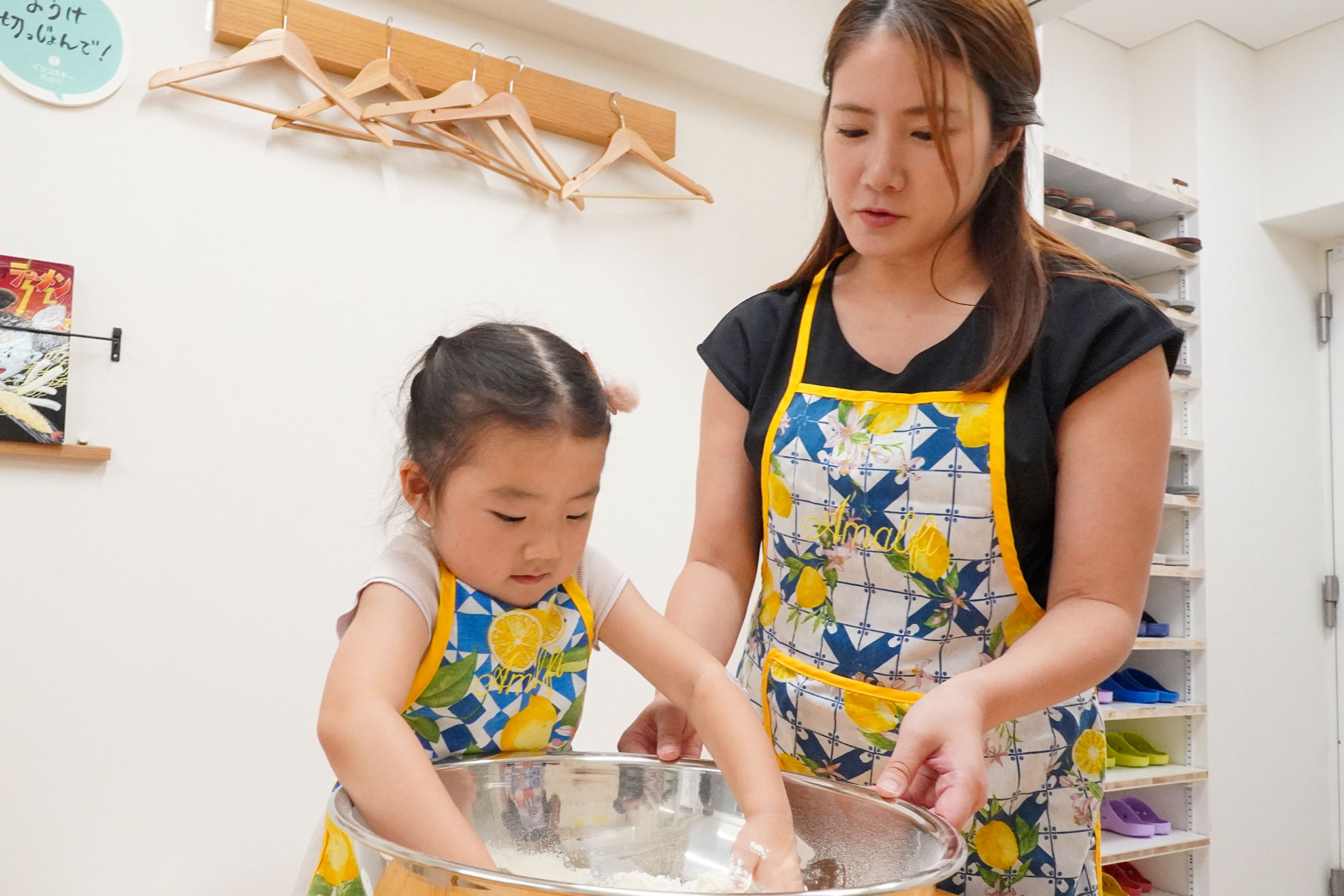お母さんと女の子が大きなボウルに手を入れて小麦粉と塩水を混ぜている。 手打ちうどん作り体験教室 2026年6月 udon-class-mother-daughter-mixing-flour-bowl.jpg – イリコスキー製麺所